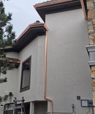 Copper seamless gutters and downspout installed on a white stucco Northern Colorado home