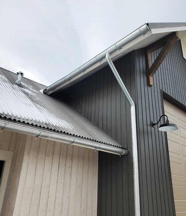 Metal roof edge with proper drip edge and seamless gutter on a modern home