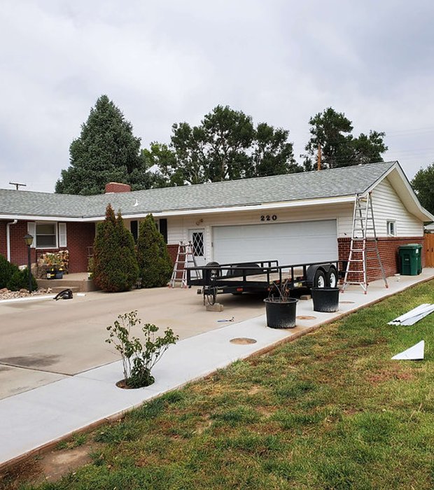 Performance Gutters installing seamless gutters on a single-story brick ranch home